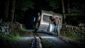 Scène nocturne réaliste d’un mari coincant une caravane de travers à Nasbinals dans le noir